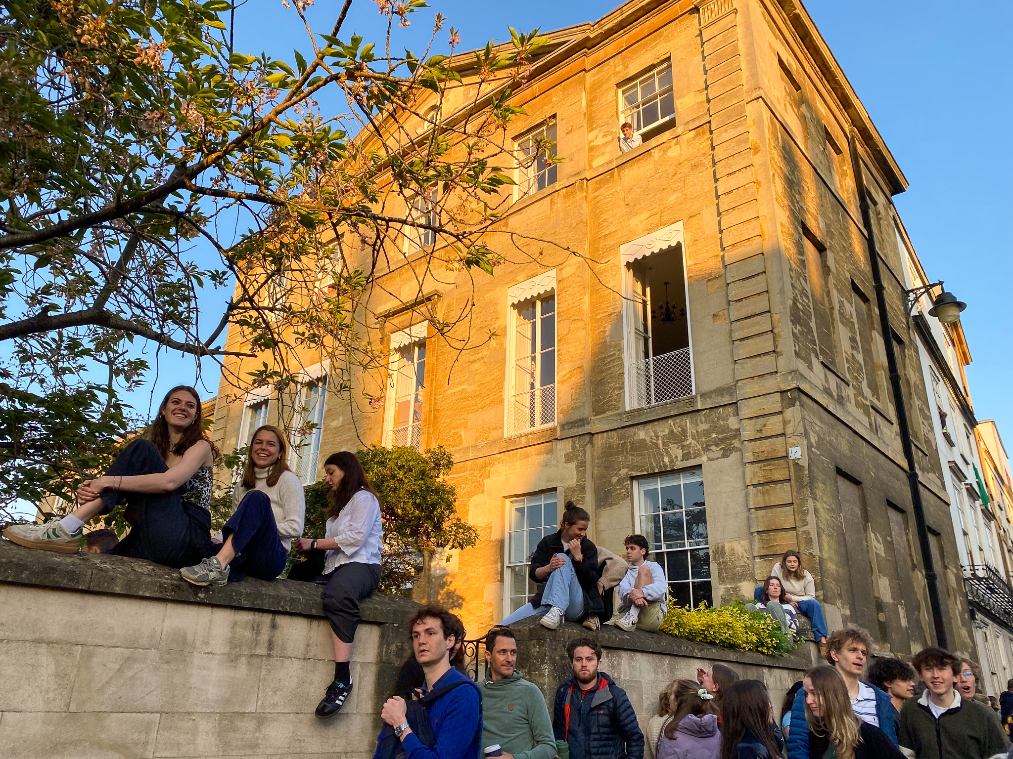 Students sitting on a wall on the High Street during May Day.