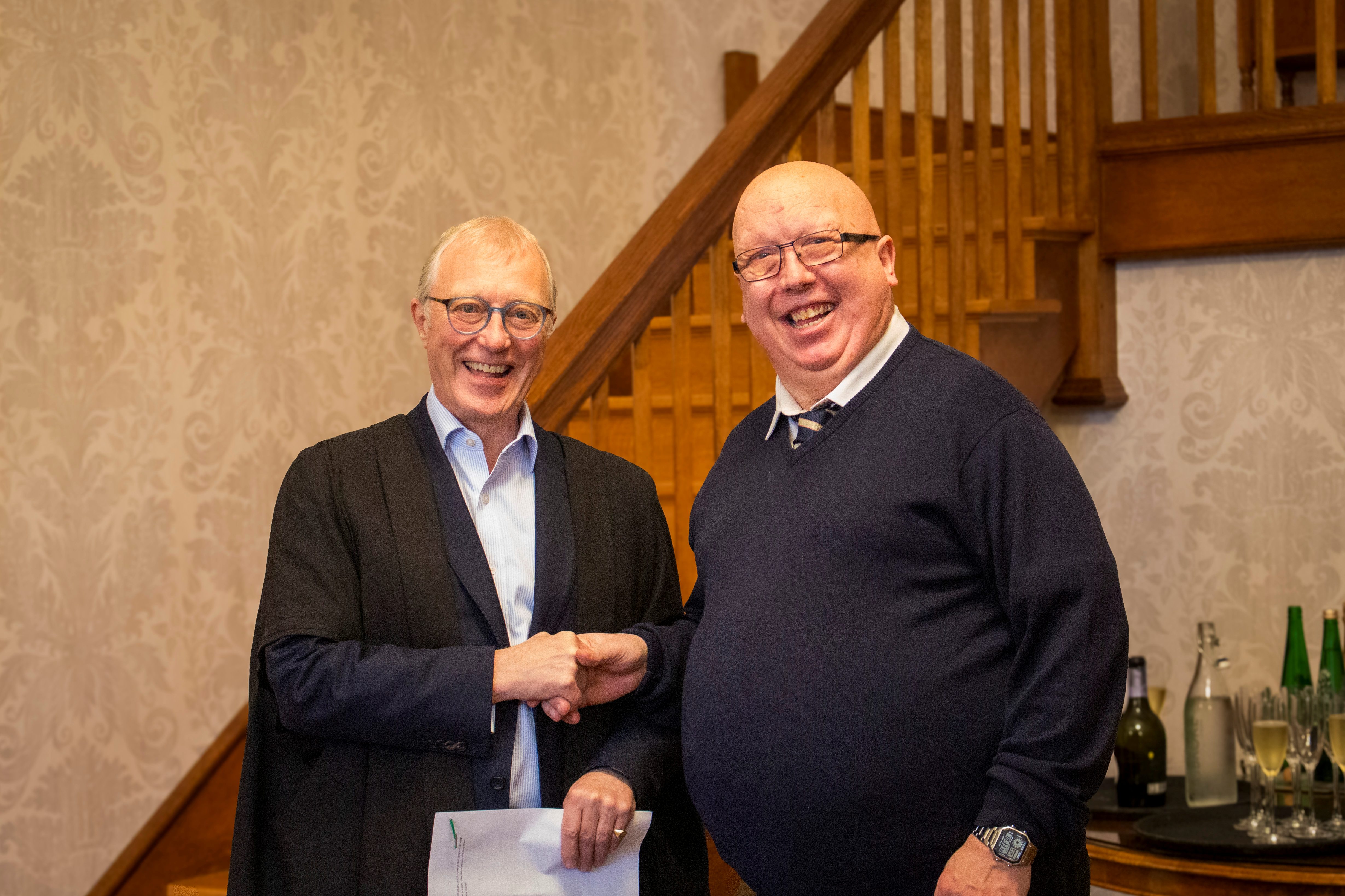 Pembroke College Porter Adrian Dempsey shaking hands with Sir Ernest Ryder.