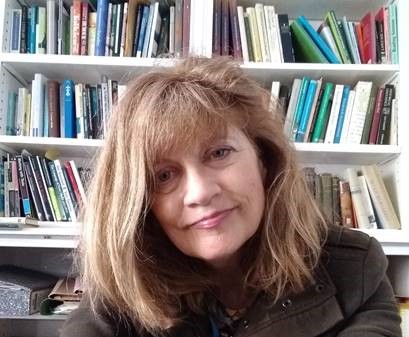 Professor Lynda Mugglestone, photographed in front of a stacked bookcase.