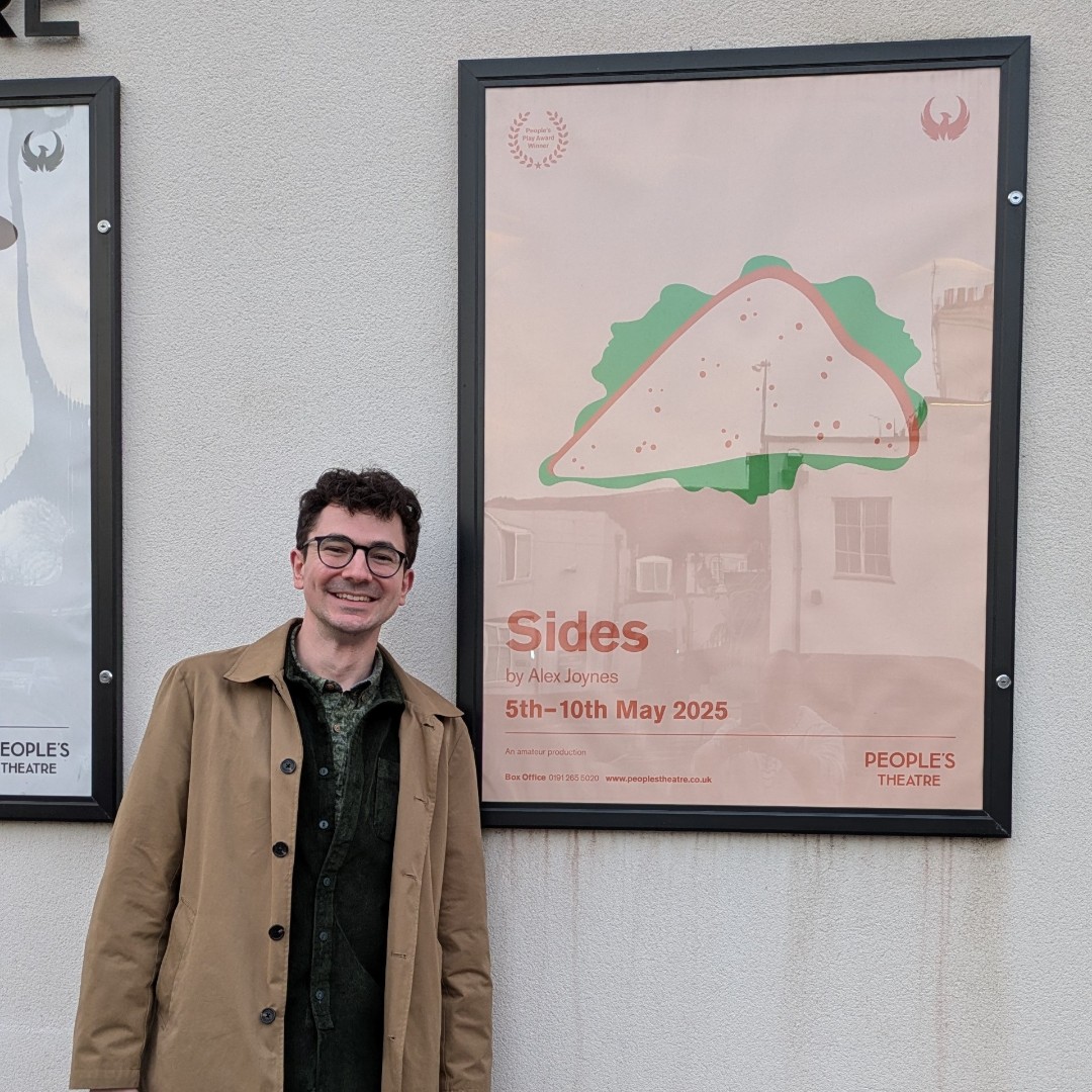 Alex Joynes in front of a poster for his new play Sides.