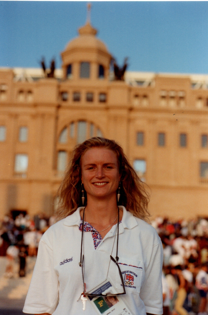 Annabel Eyres pictured at the 1992 Olympics in Barcelona, wearing a white Team GB polo shirt and standing in front of a beige building.