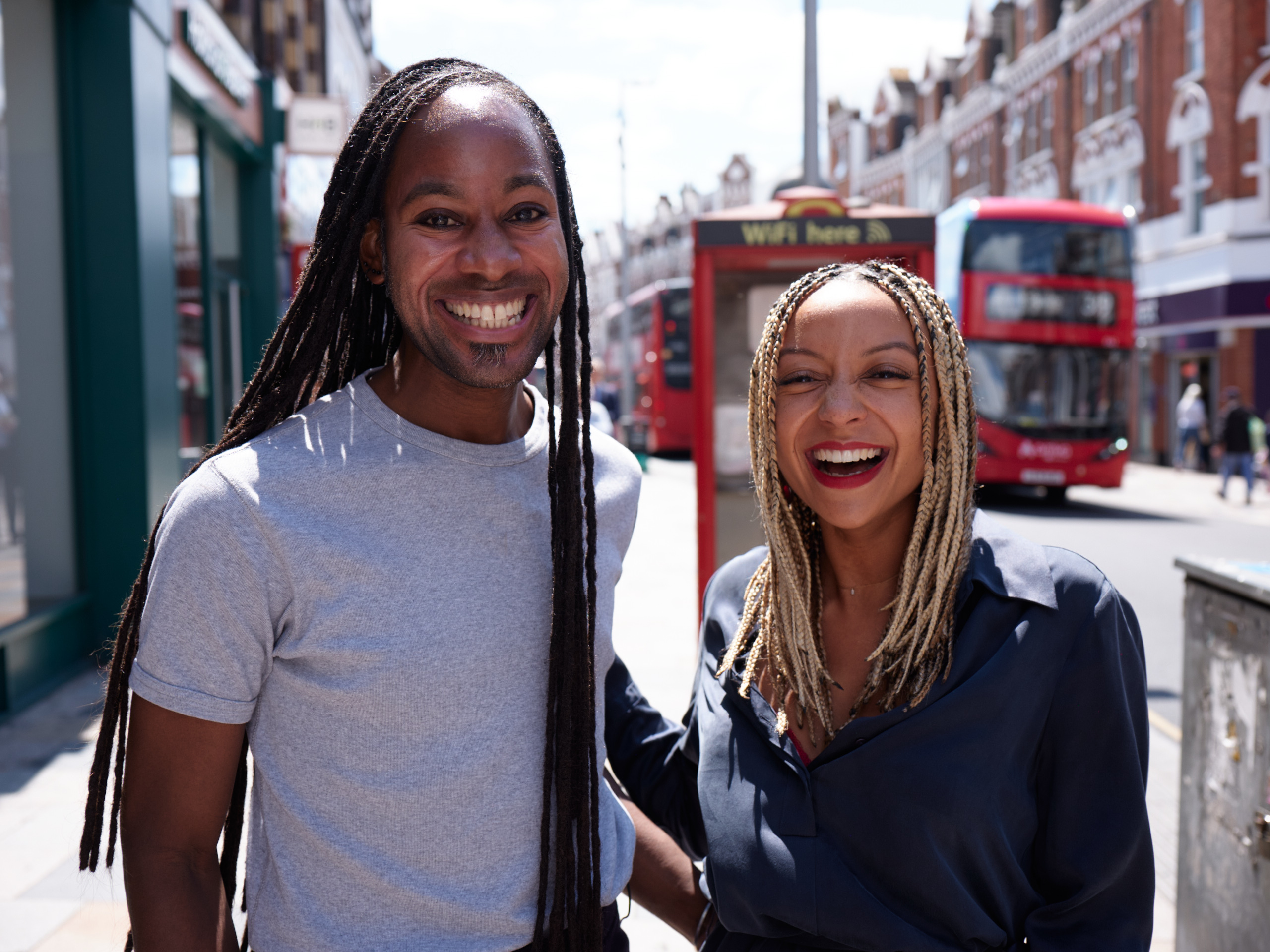 Dr Chantelle Lewis (right) and Professor Jason Arday (left) smile at the camera on a busy street in London.