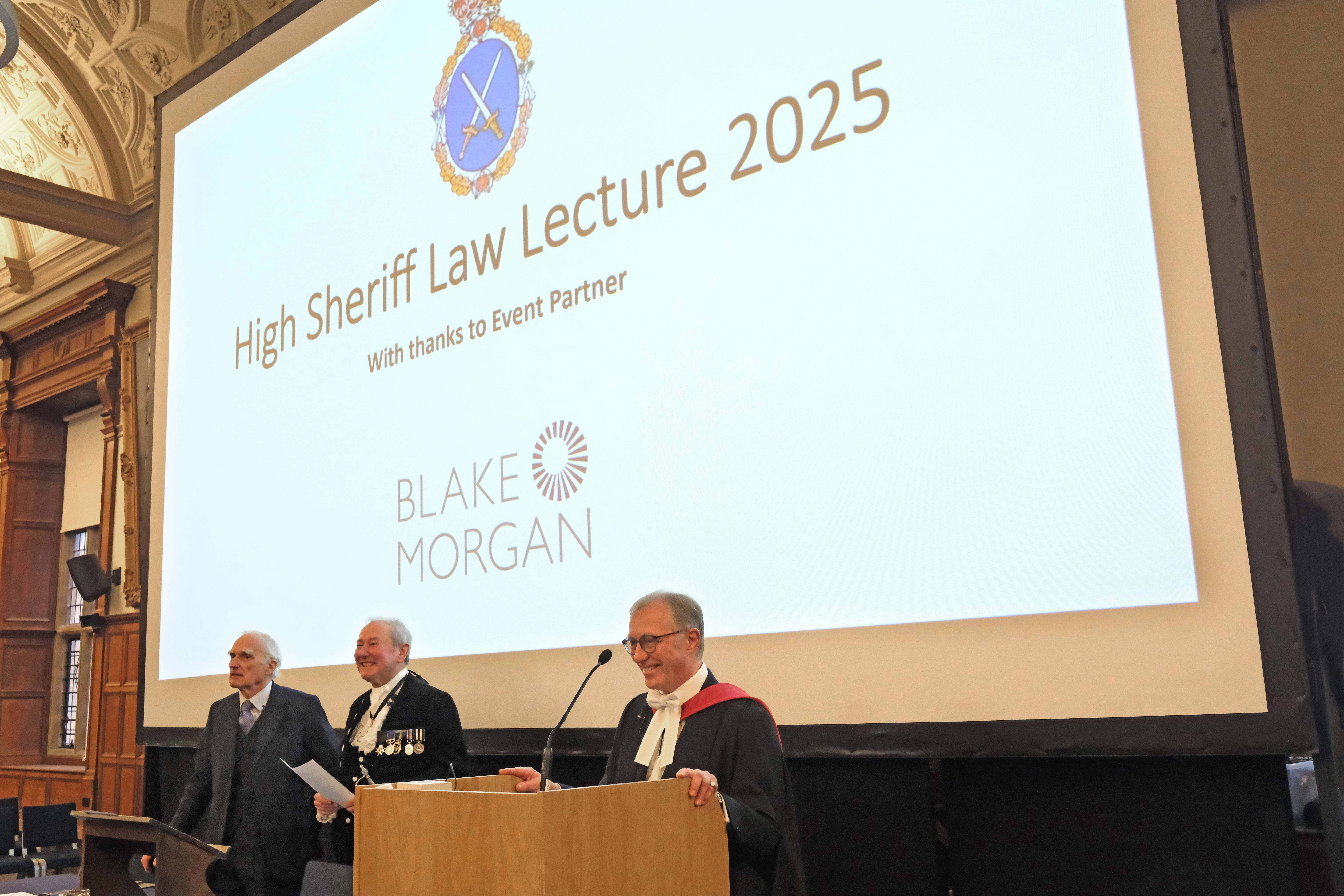 The Rt Hon Sir Ernest Ryder standing behind the lecture podium.
