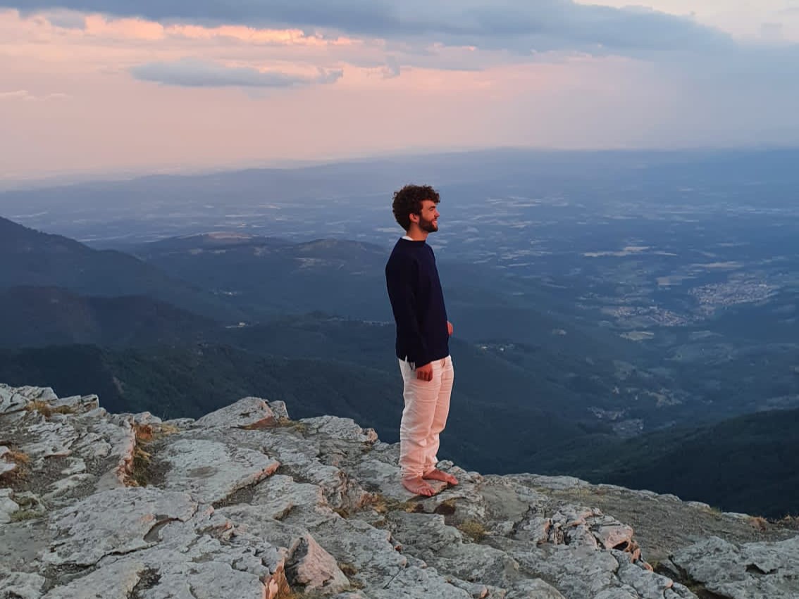 Henry standing on a mountain with a mountainous background.