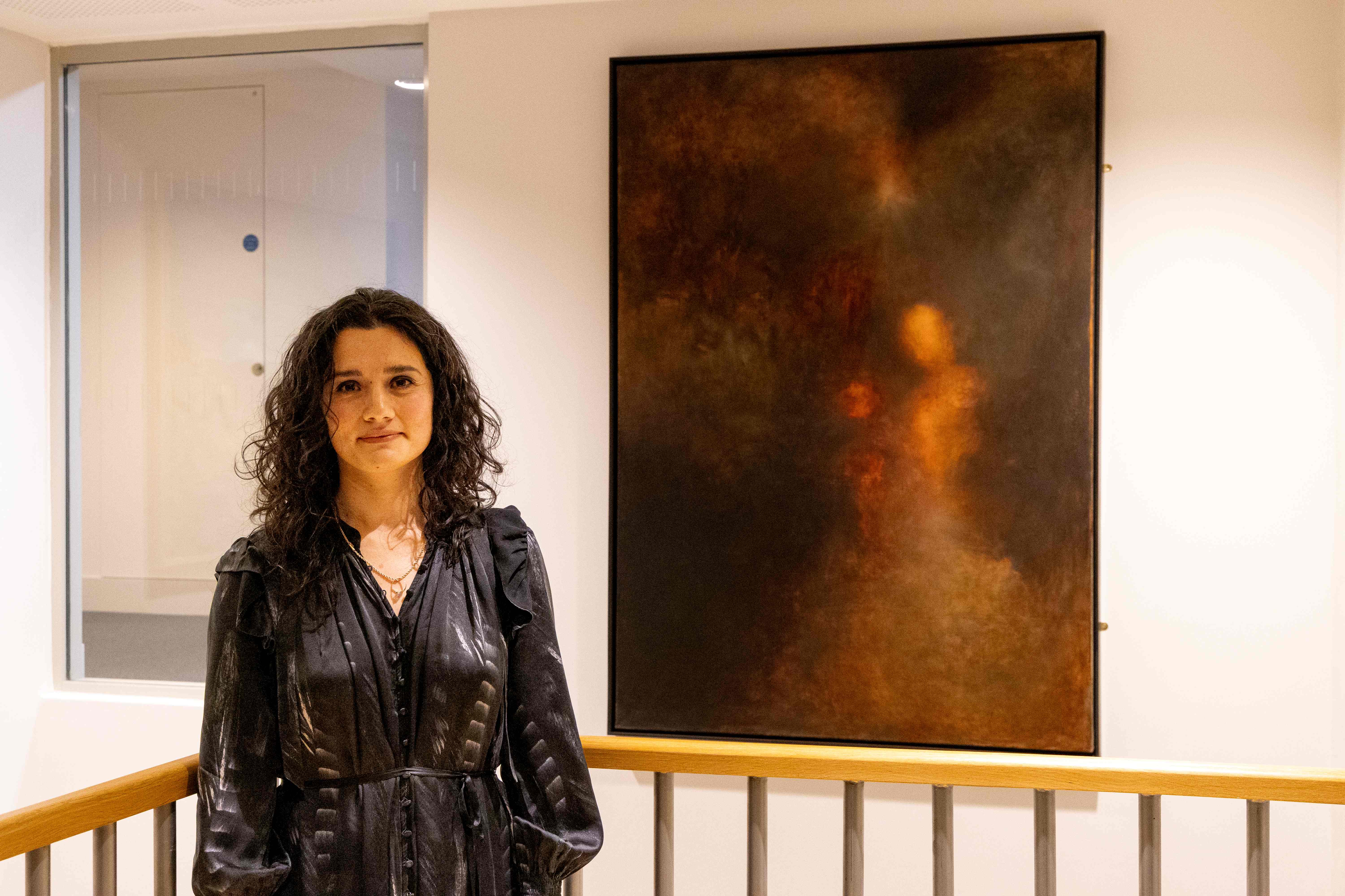 Chantal Meza standing beside her painting 'Dreams of Disappearance'
