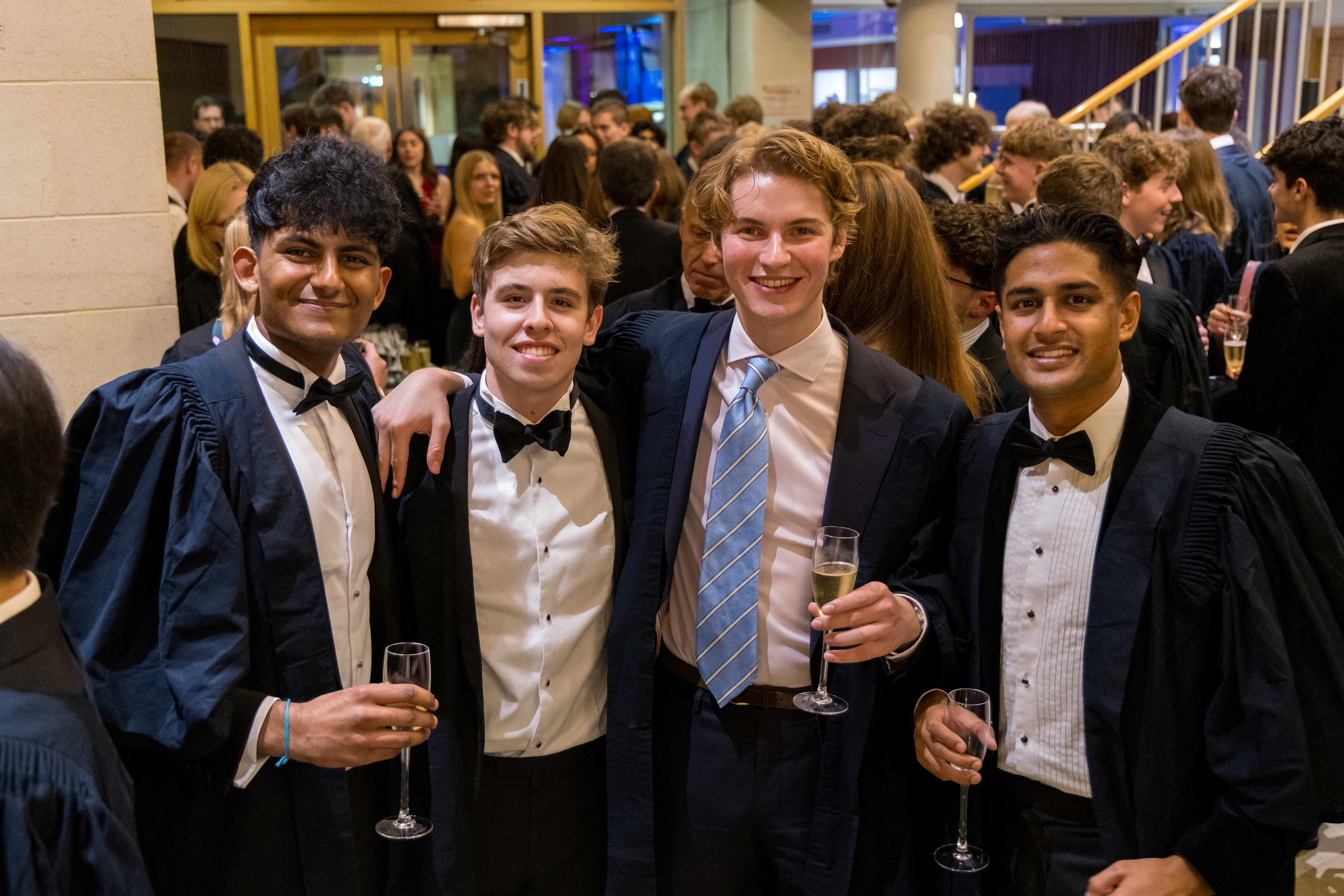 Four Pembroke students smiling in their Scholars gowns at the Scholars Lecture.