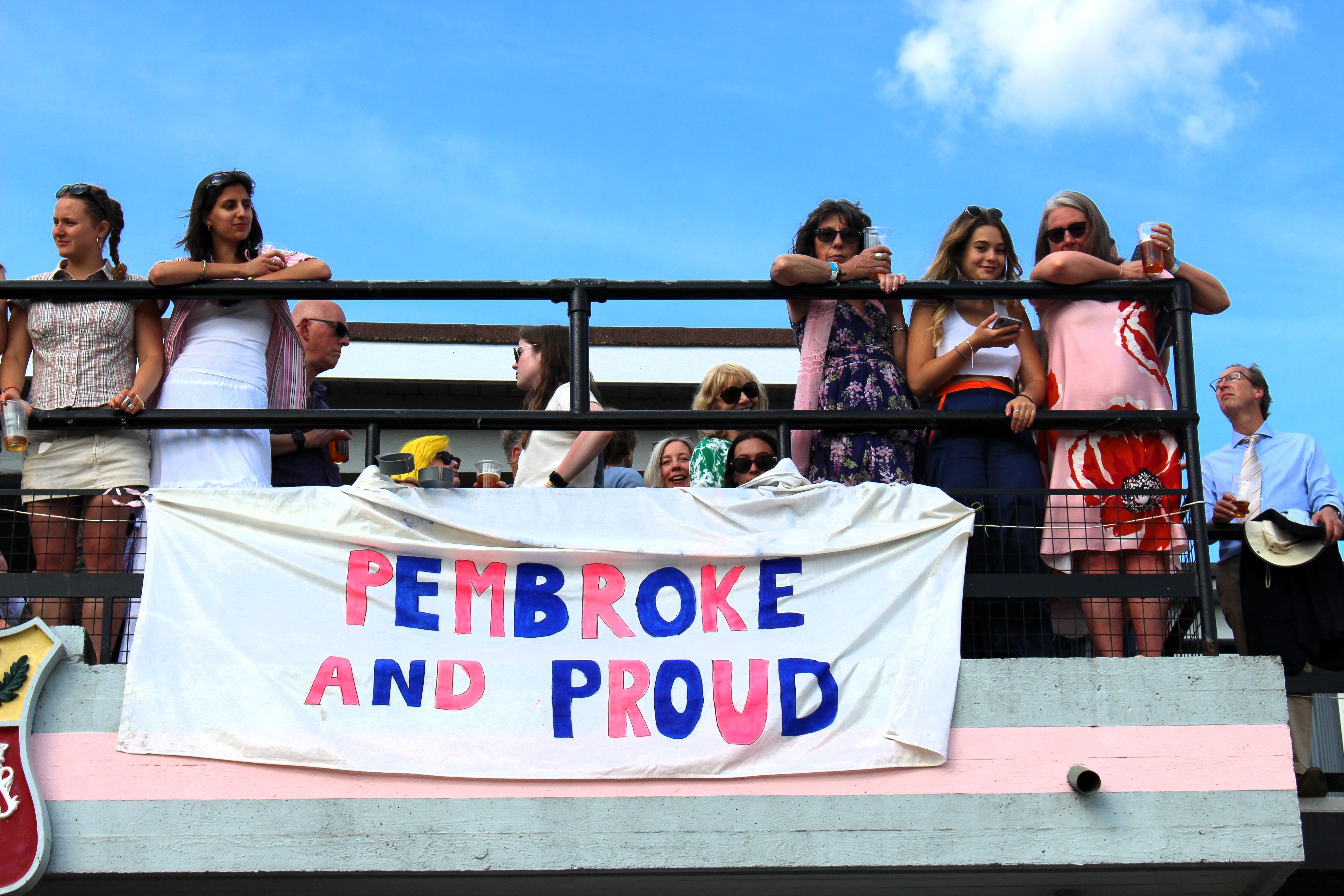 Spectators watch from the top of the Pembroke Boathouse, which is adorned with a sign saying 'Pembroke and Proud'.