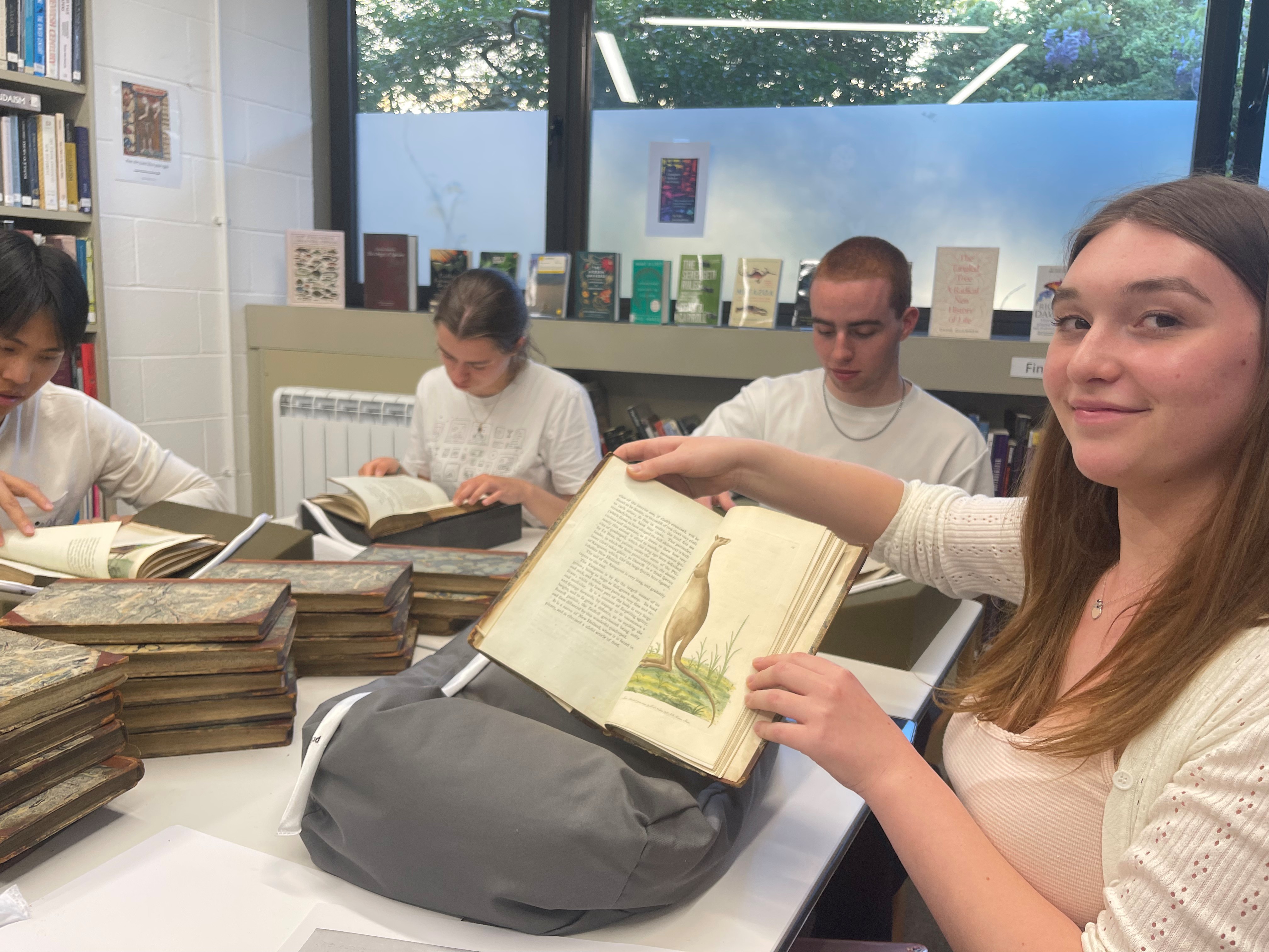 Pembroke Biology undergraduates looking through old textbooks of flaura and fauna