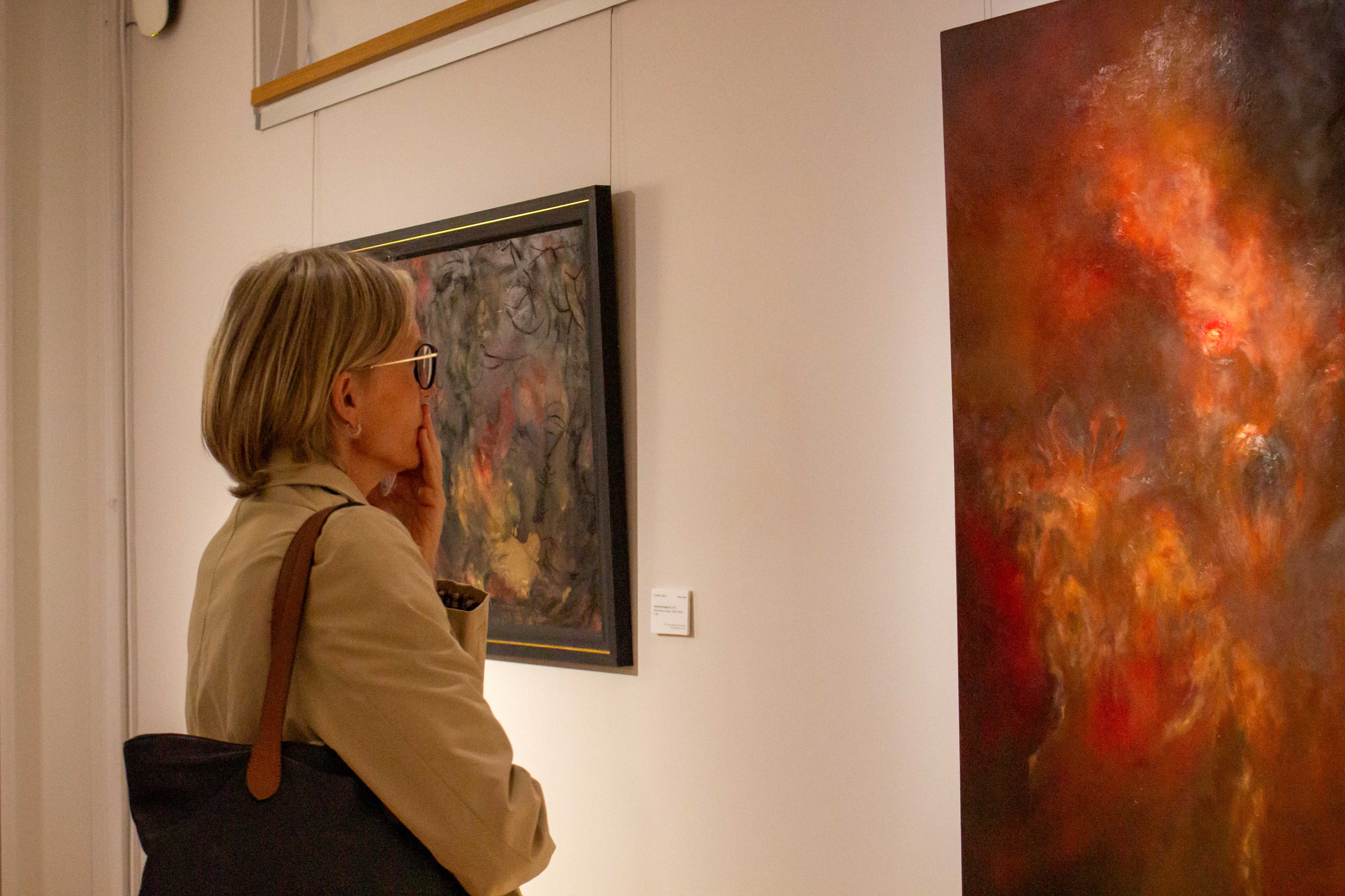 A woman looking at one of Chantal Meza's paintings at Pembroke JCR Art Gallery's Disappearance of Worlds exhibition.