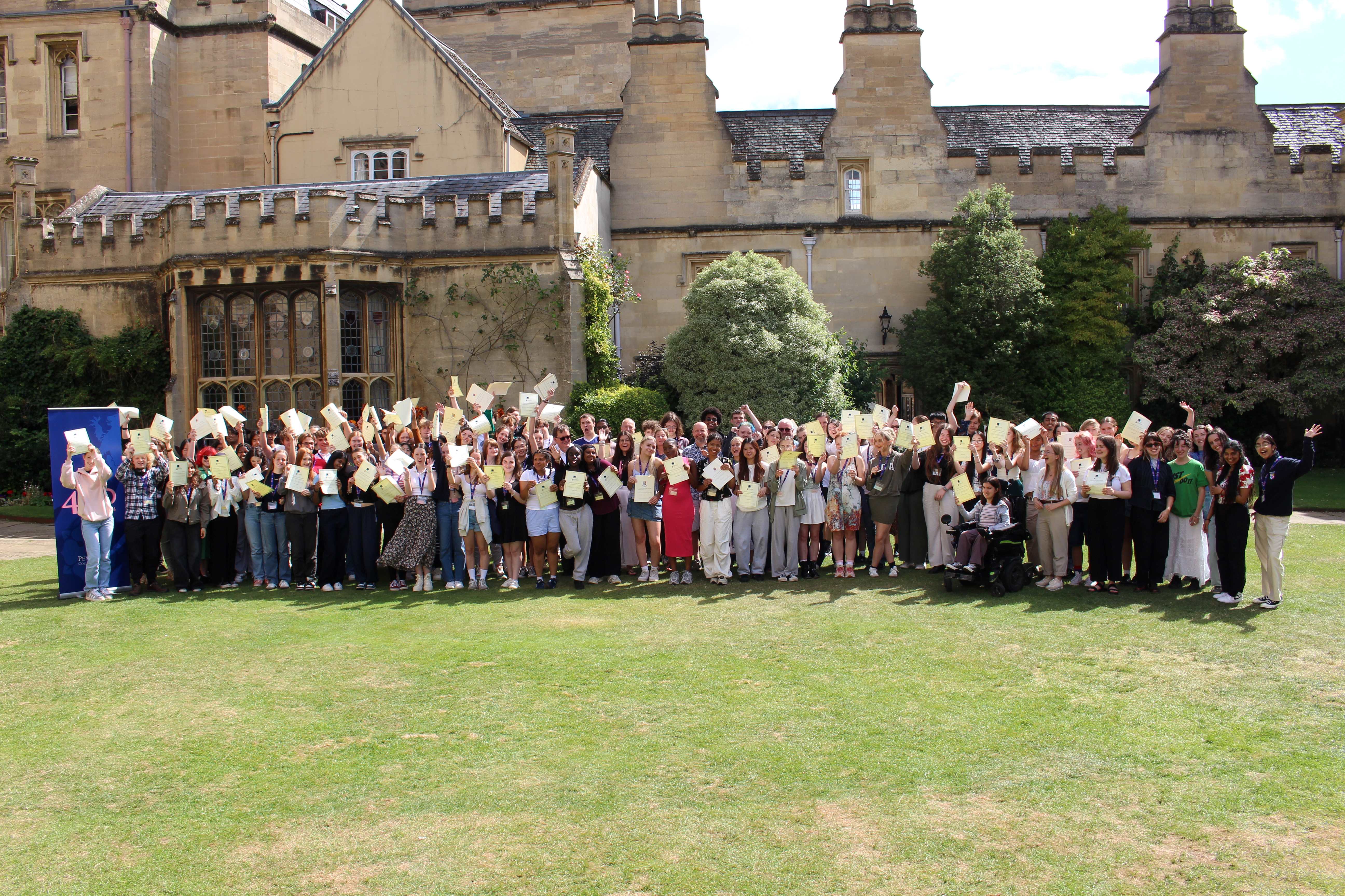 A group of OxNet students standing on the grass in the quad and holding up their certificates