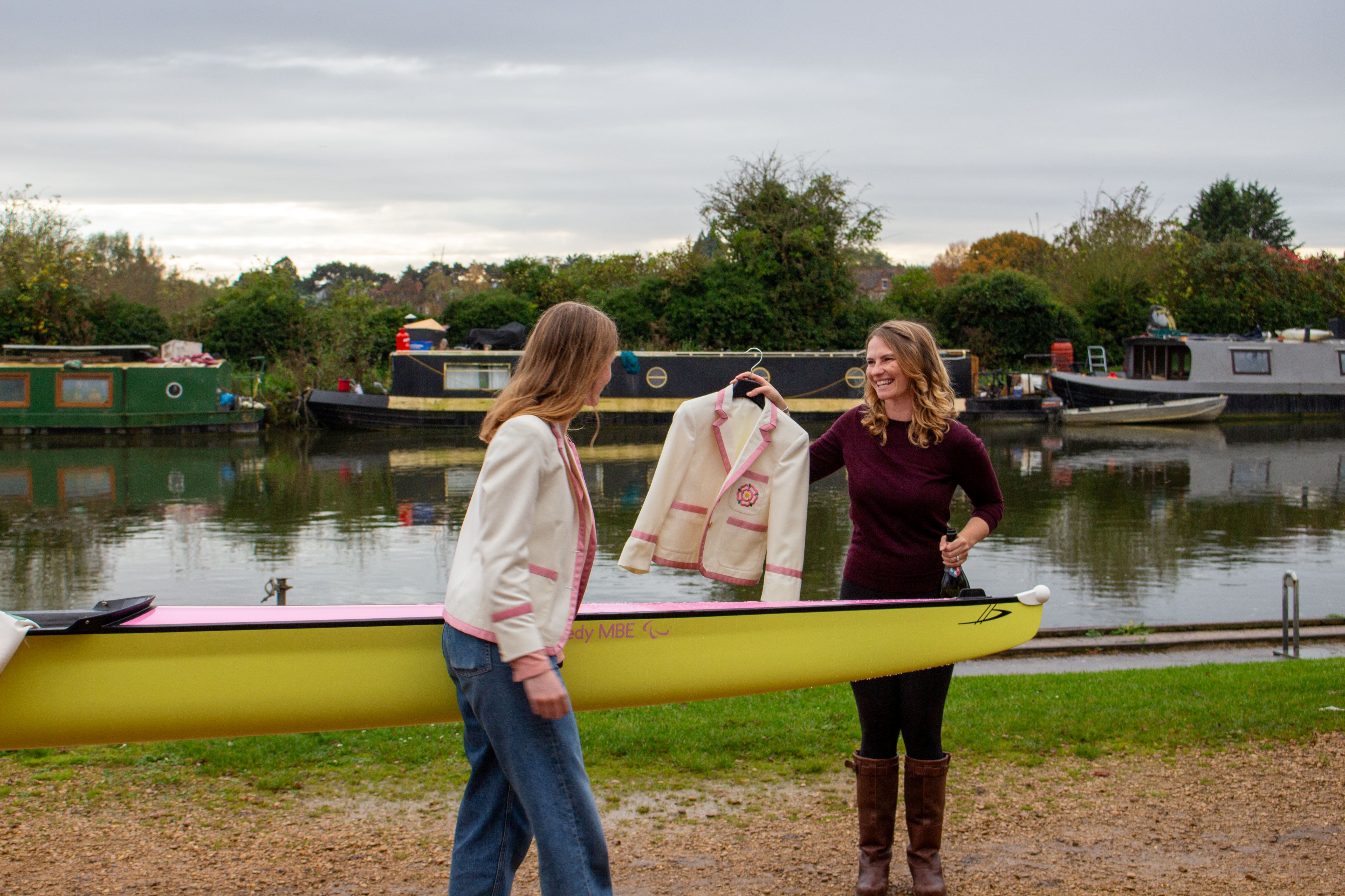 Erin receiving a PCBC blazer from Georgia Douglas, both stood by the new PCBC women's boat.