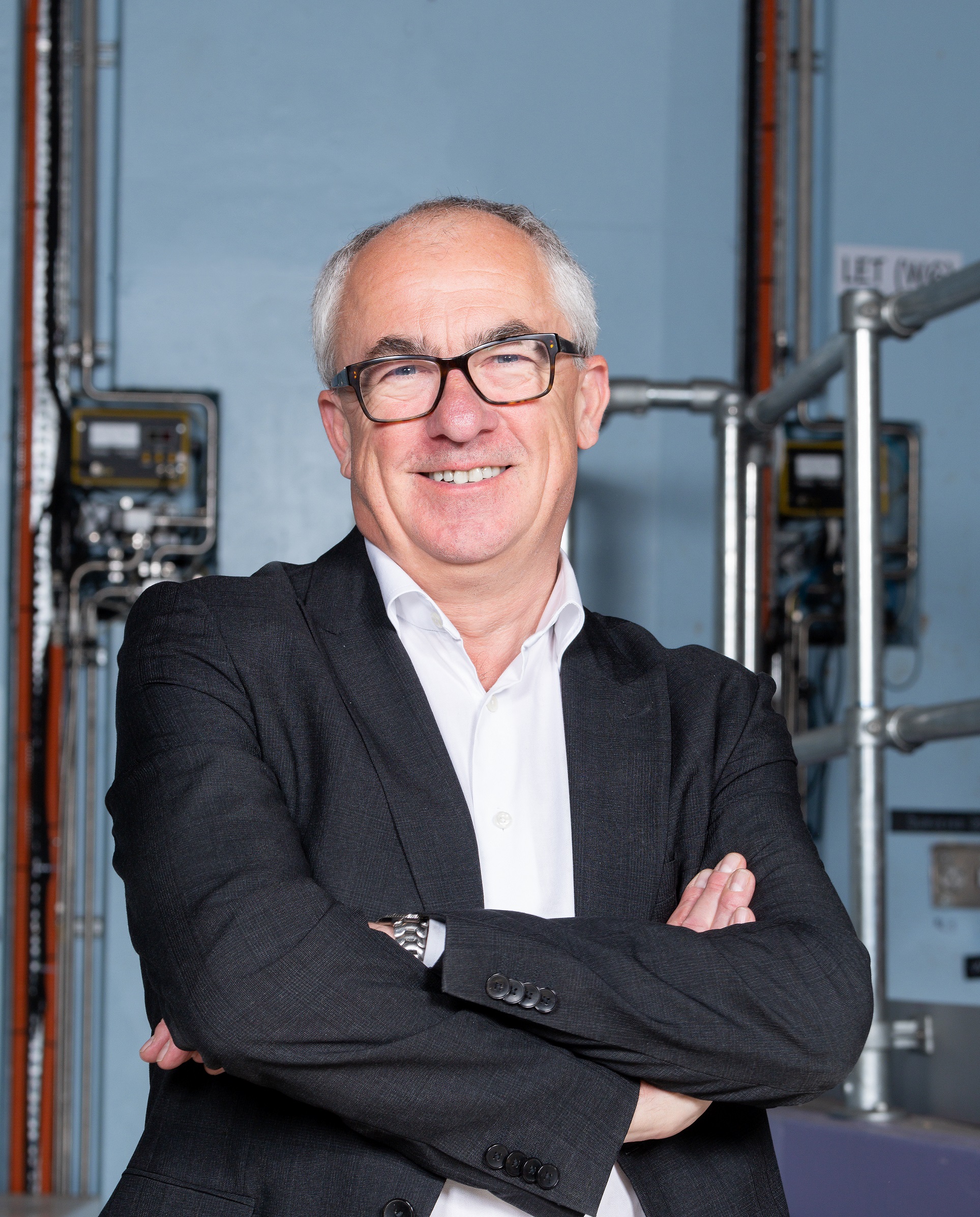 An upper body shot of Mark smiling with his arms folded.