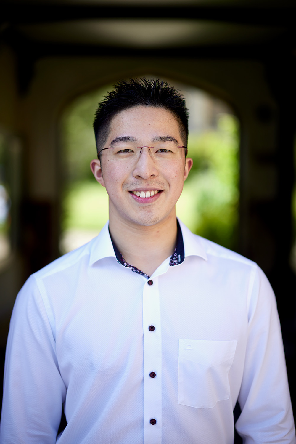 Head shot of Oscar Lu, smiling, with Chapel Quad in background