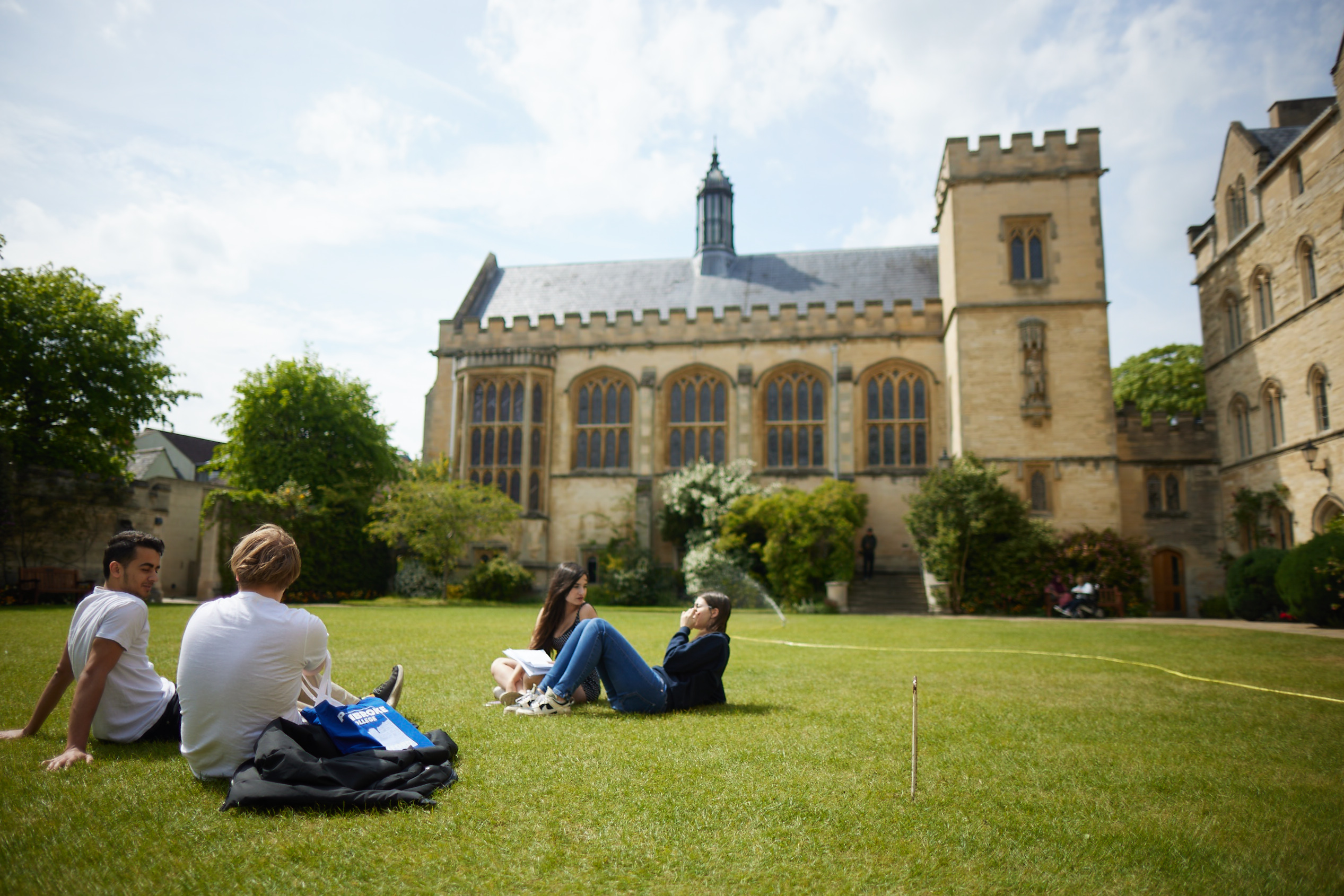 Students sitting on the grass in Chapel Quad, Pembroke College. Dining Hall building can be seen in background.