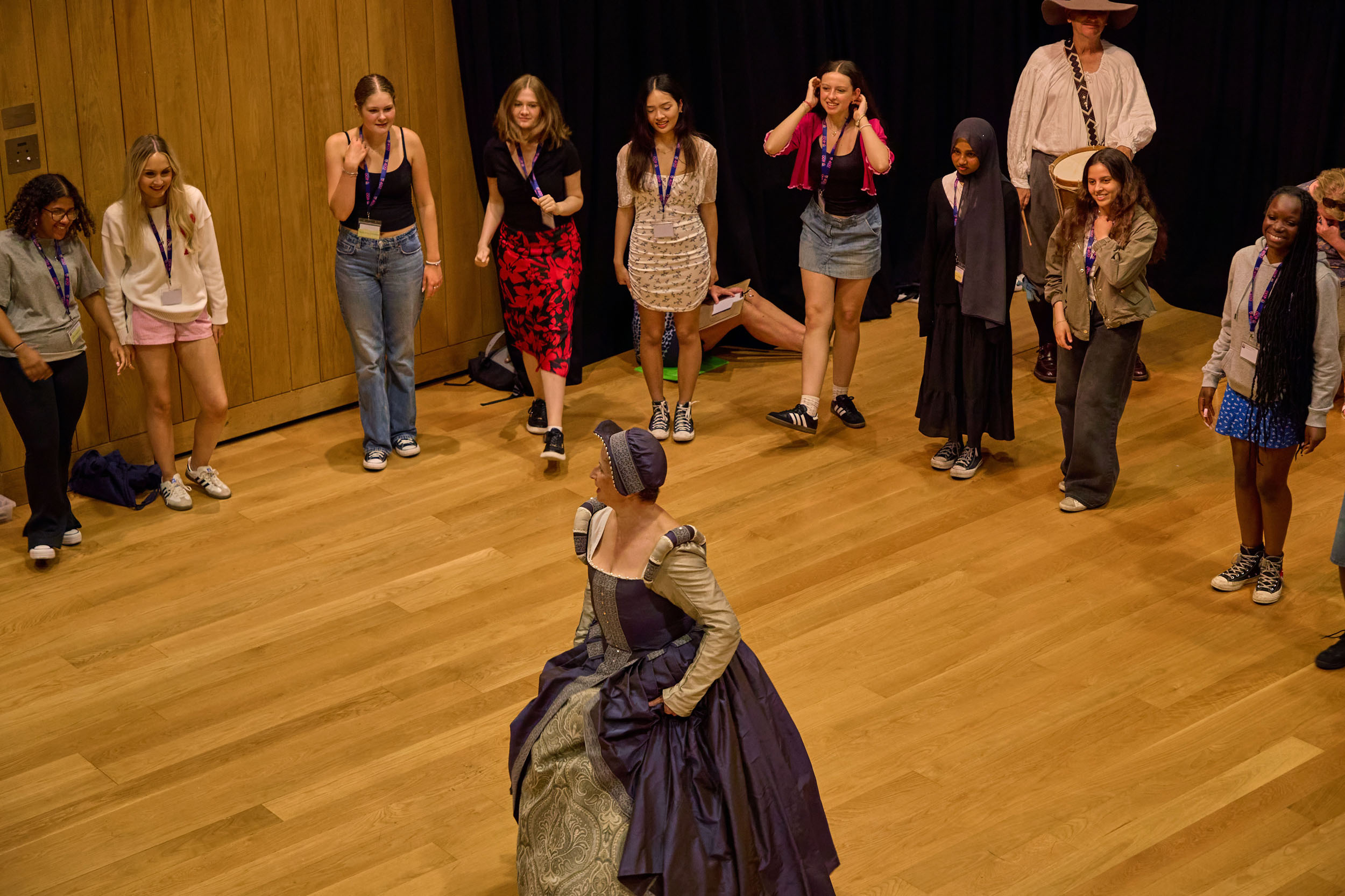 A dancer in period dress leads students in 17th century dance.