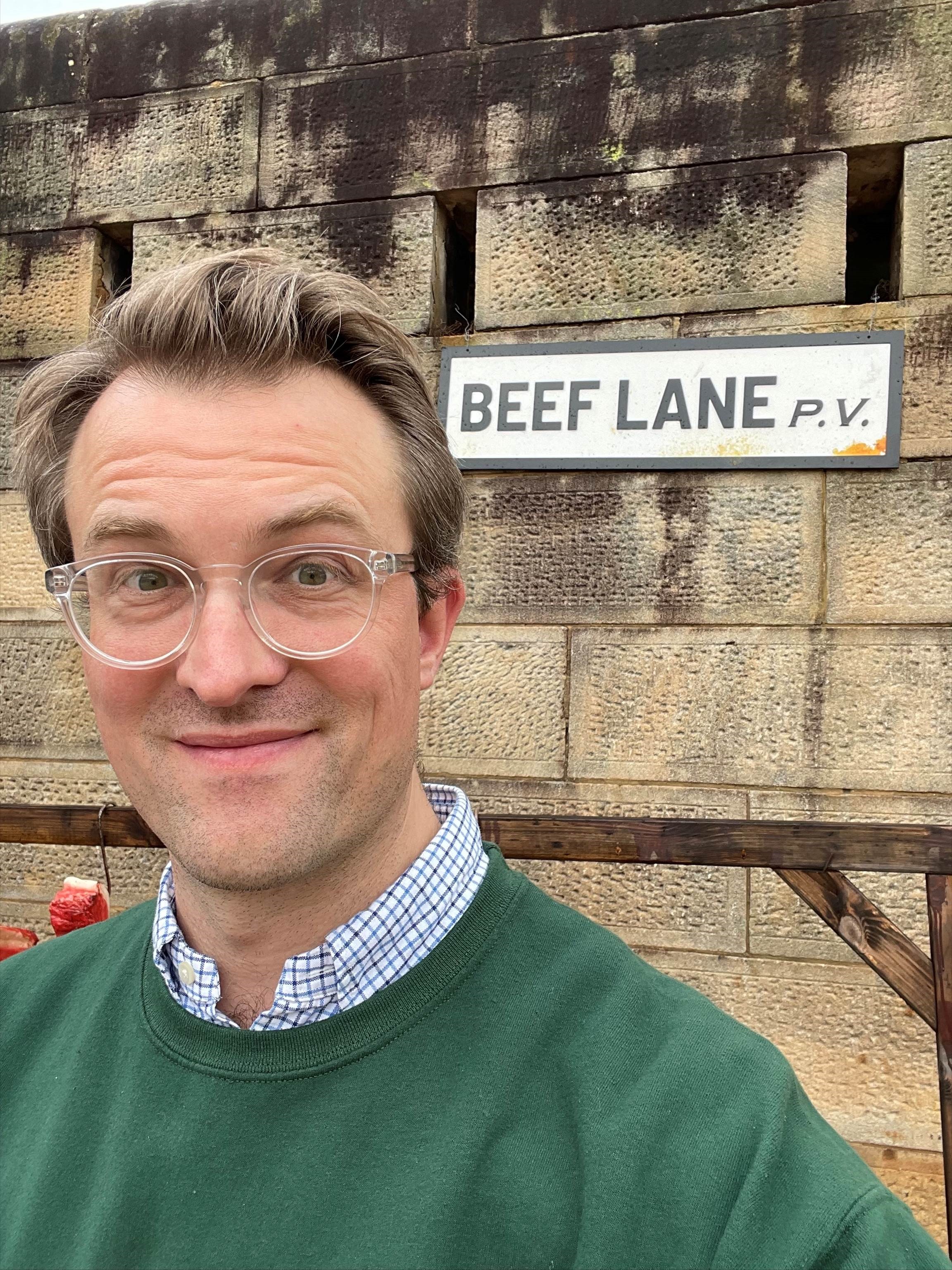 James McNamara poses next to the fictional 'Beef Lane' on set.