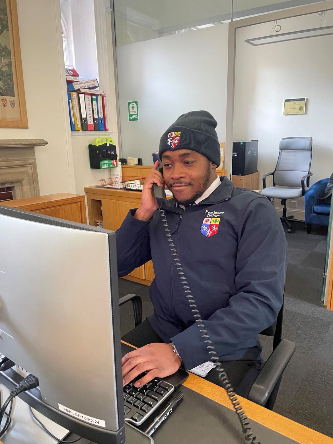 Spencer Solomon, Lodge Porter, pictured at the desk in the Lodge posing with a phone.