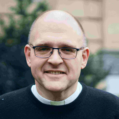 The Reverend Dr Andrew Teal smiles at the camera in front of the Chapel.