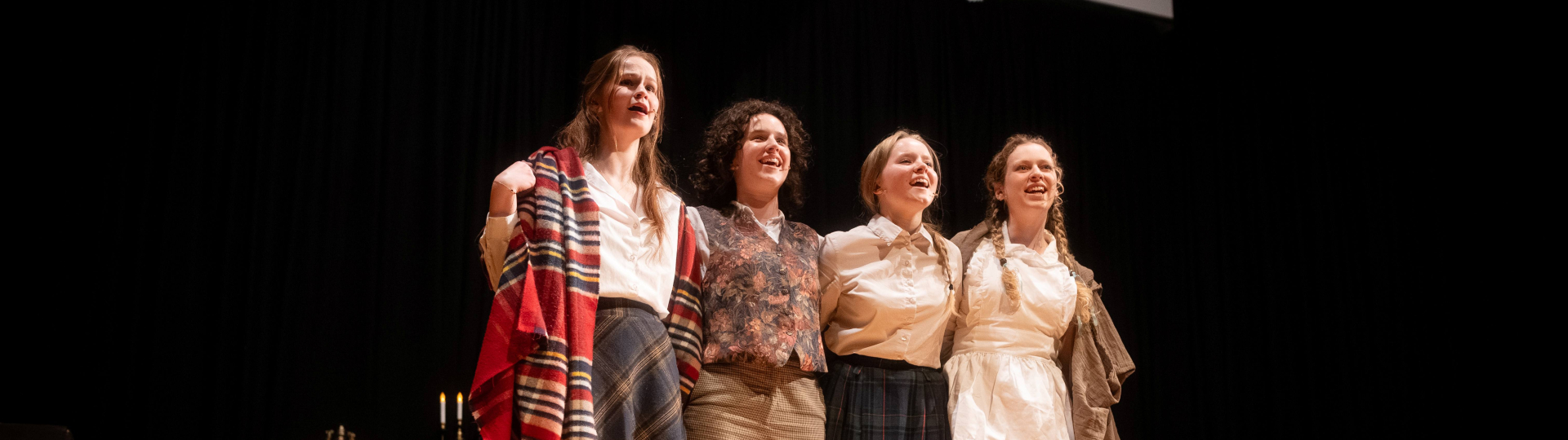 Four students in costume singing together on stage