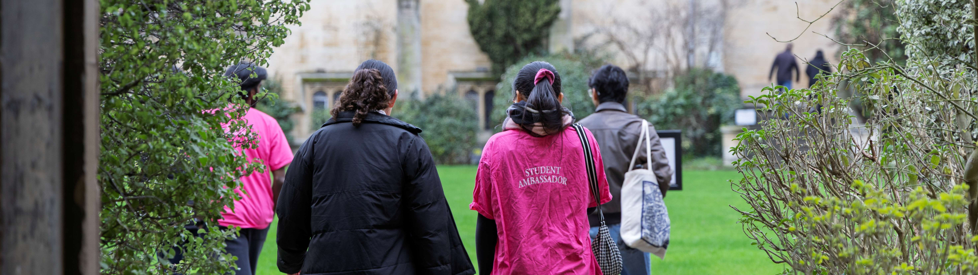 student in pink student ambassador tshirt walking into Chapel Quad