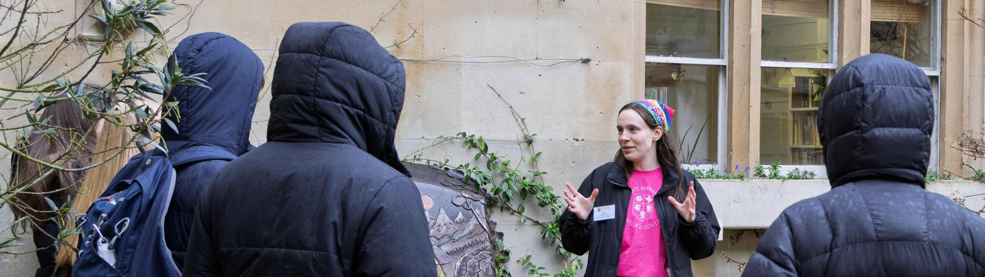 student in pink student ambassador tshirt talking to offer holders in Old Quad