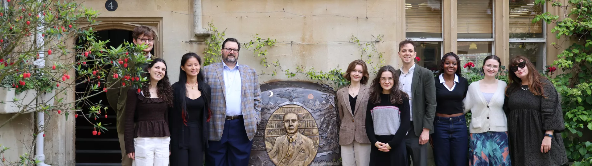 Tolkien Committee and Brandon Sanderson stood with Tolkien memorial in front of stone wall
