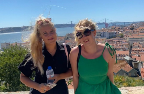 Olivia and Cassie leaning against wall with Lisbon sea view behind