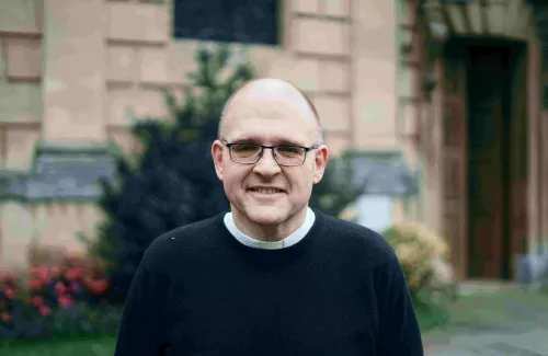 The Reverend Dr Andrew Teal smiles at the camera in front of the Chapel.