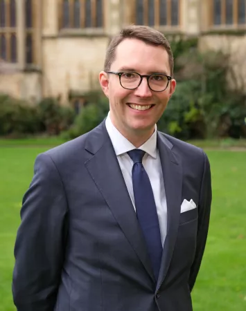 Jacob Ward stood outdoors smiling, with Hall in background
